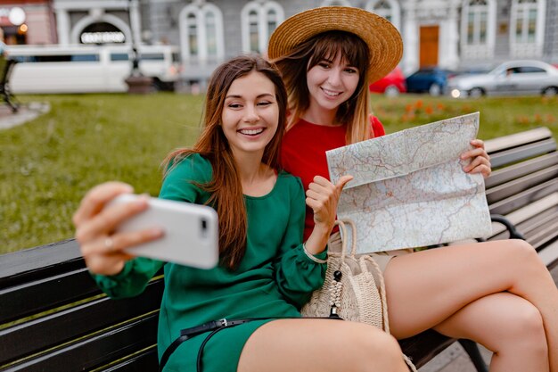 Élégantes jeunes femmes voyageant ensemble en Europe vêtues de robes et d'accessoires à la mode du printemps