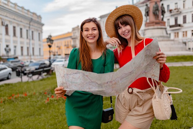 Élégantes jeunes femmes voyageant ensemble en Europe vêtues de tenues et d'accessoires à la mode du printemps