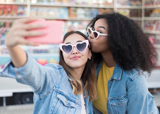 Élégantes jeunes filles prenant un selfie ensemble