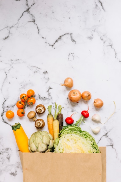 Légumes débordent d&#39;un sac en papier brun sur fond de marbre