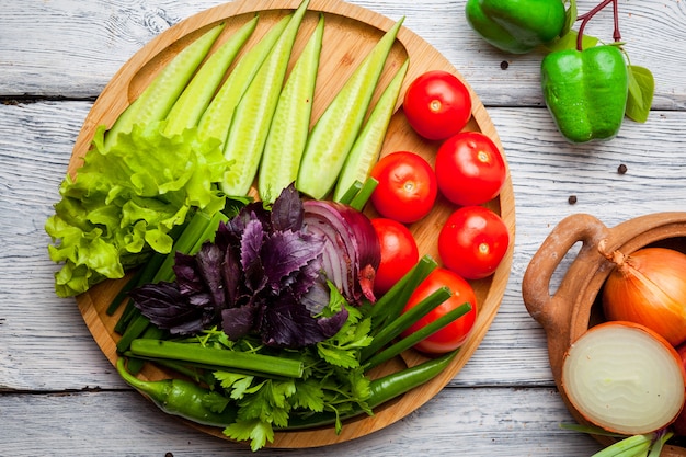 Légumes frais concombre, tomate, oignon, poivre sur planche à découper en bois