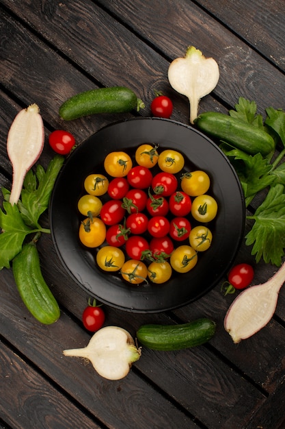 Légumes frais concombres mûrs tomates rouges et jaunes et radis sur un bois