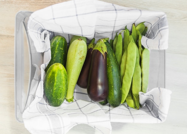 Légumes frais récoltés dans le récipient avec serviette