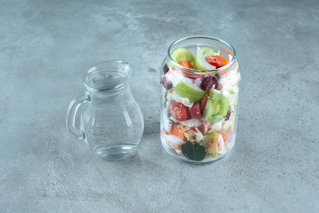 Légumes hachés dans un bocal en verre avec de l'eau.