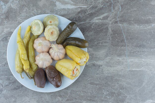 Légumes marinés frais faits maison sur plaque blanche.