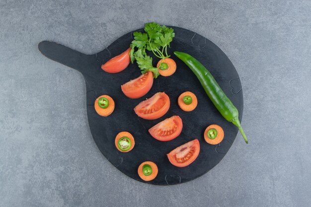 Légumes mûrs tranchés sur une planche à découper noire.