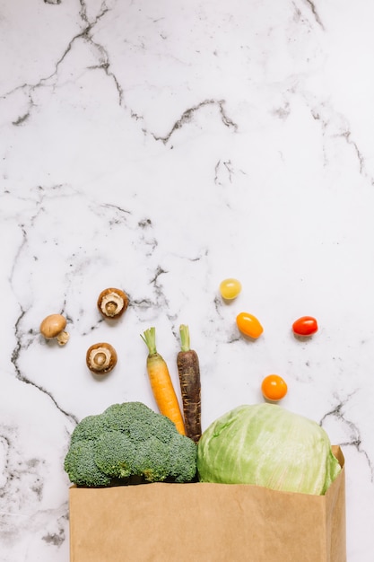 Légumes renversant d'un sac en papier brun sur le comptoir de cuisine en marbre