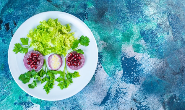 Photo gratuite légumes verts tranchés et arilles de grenade sur une assiette