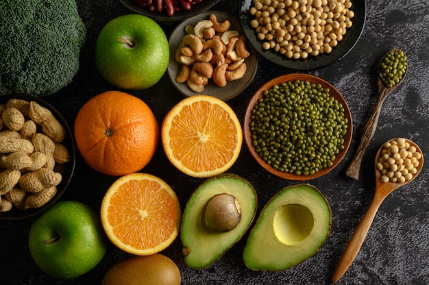 Légumineuses et fruits sur une surface de sol en ciment noir.