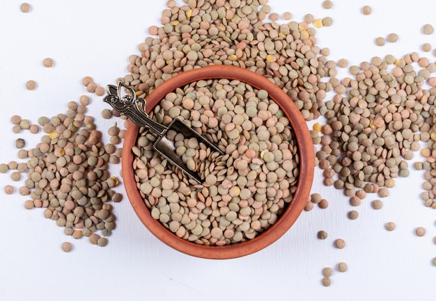 Lentilles vertes dans un bol brun et une cuillère à épices en fer