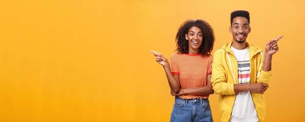 Photo gratuite lequel dit vrai joyeux et amical beau couple femme afro-américaine pointant à gauche