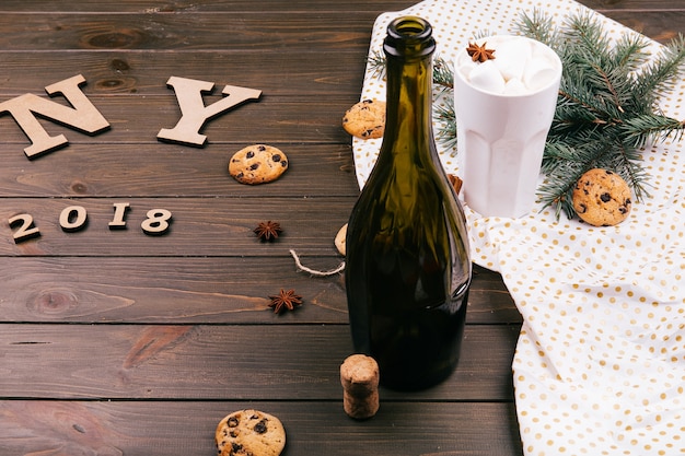 Les Lettres En Bois «ny 2018» Se Trouvent Sur Le Sol Entourées De Biscuits, Branches De Sapin, Chocolat Chaud, Bouteille De Vin Vide