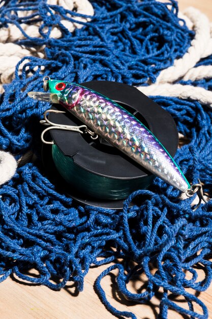 Leurre de pêche avec crochet; moulinet sur filet de pêche bleu sur une surface en bois