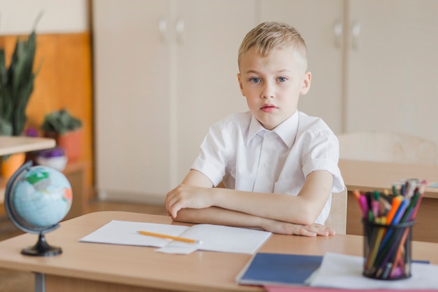 Élève assis avec les mains sur le bureau dans la salle de classe