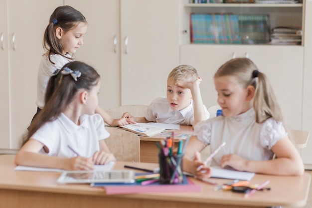 Élèves parlent en salle de classe assis à des bureaux