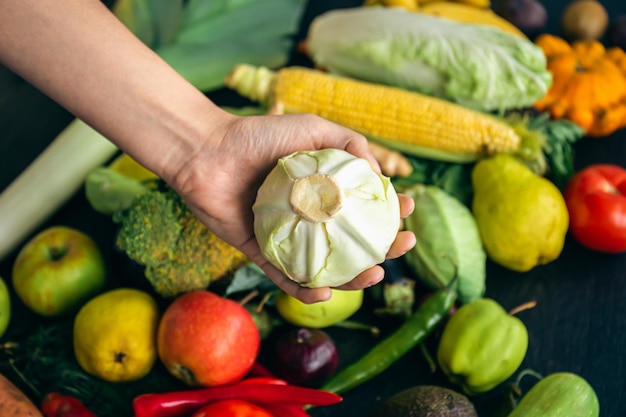 Libre de chou dans une main de femme sur la table de la cuisine parmi les légumes