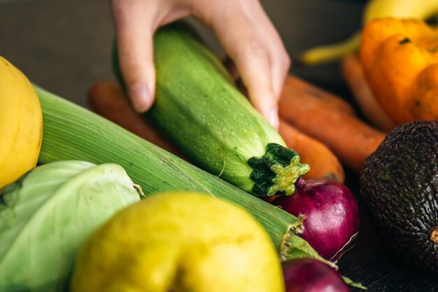 Libre de courgettes dans les mains des femmes parmi les légumes sur la table de la cuisine