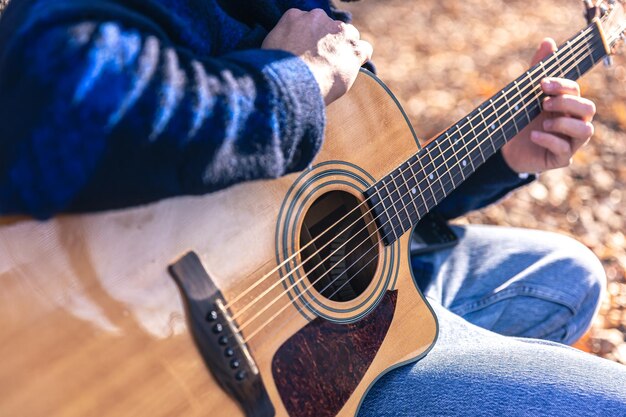 Libre un homme joue une guitare acoustique dans la forêt d'automne