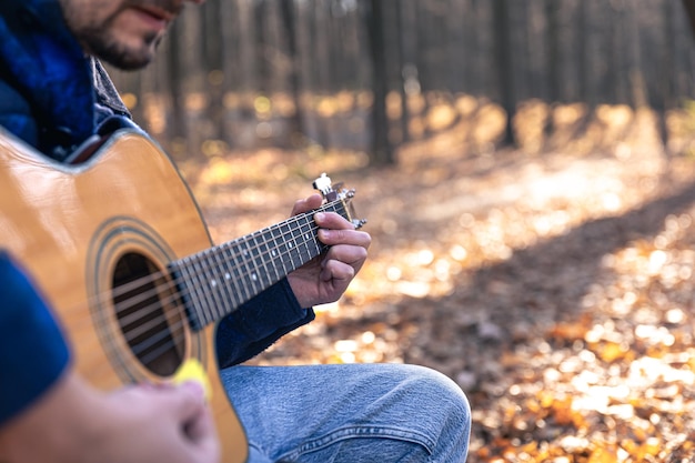 Libre un homme joue une guitare acoustique dans la forêt d'automne