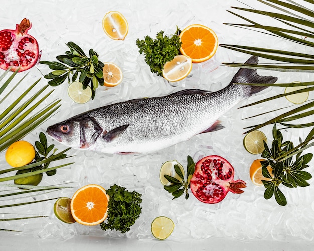 Photo gratuite lieu de poisson cru sur glace entouré de tranches de fruits