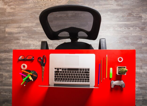 Lieu de travail de bureau avec ordinateur portable et papeterie sur une table rouge en bois rouge