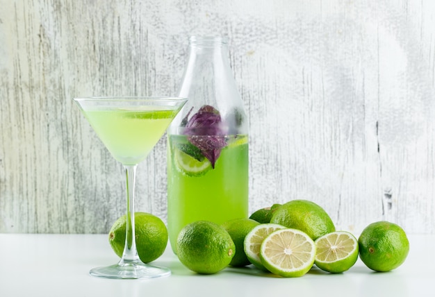 Limonade aux citrons, feuilles de basilic en verre et bouteille sur blanc et grungy,