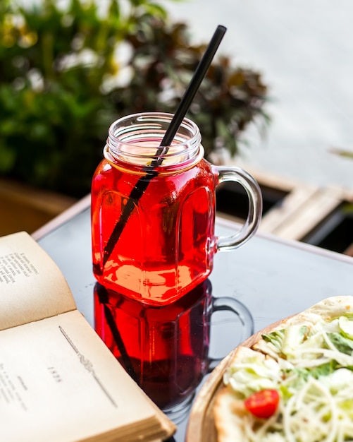 Limonade aux fruits rouges sur la table dans le pot en verre avec vue latérale de la paille