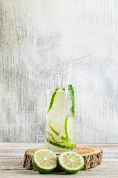 Limonade dans un verre au citron, basilic, planche à découper vue latérale sur bois et grungy