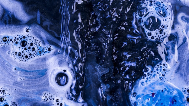 Liquide bleu bouillant avec mousse et gouttes