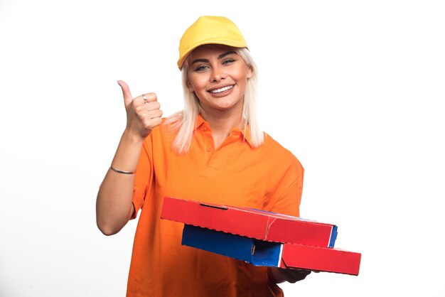 Livraison de pizza femme tenant une pizza sur fond blanc abandonnant le geste de pouce en l'air. Photo de haute qualité