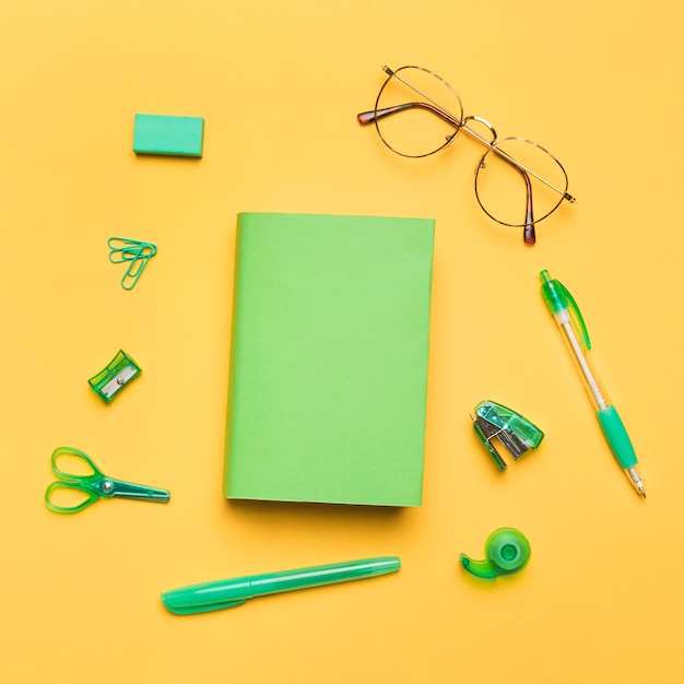 Livre en couverture colorée entouré de fournitures scolaires vertes