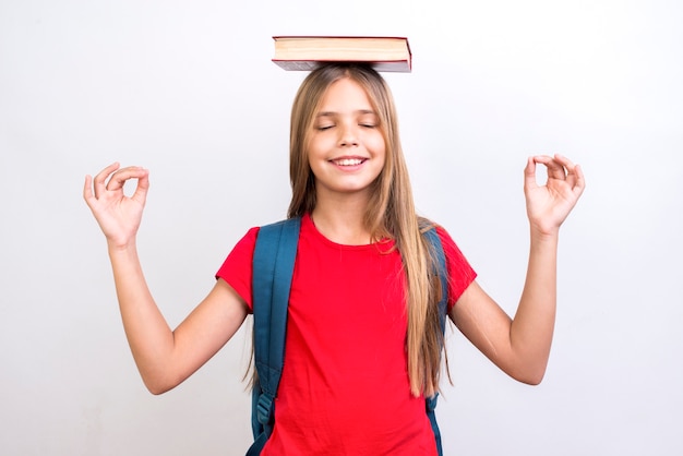 Photo gratuite livre d'écolière diligent portant un livre sur la tête