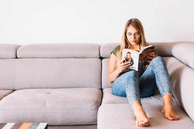 Livre de lecture de femme assise sur un canapé