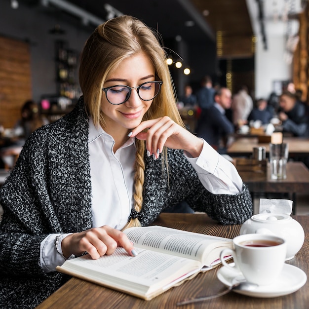 Livre de lecture de femme souriante au café