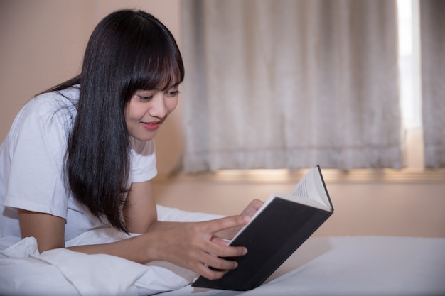 Photo gratuite livre de lecture fille et boire un café au lit le matin