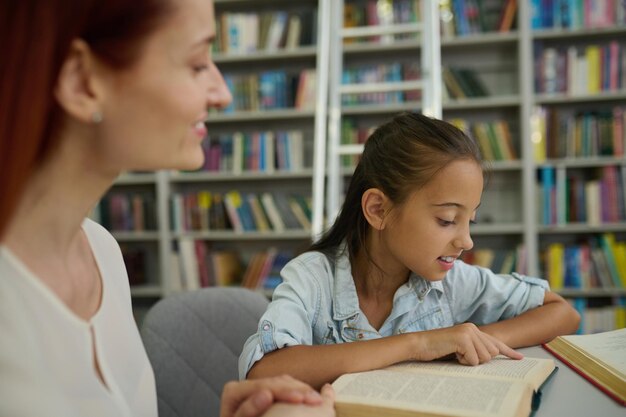 Livre de lecture de fille touchant la page avec le doigt