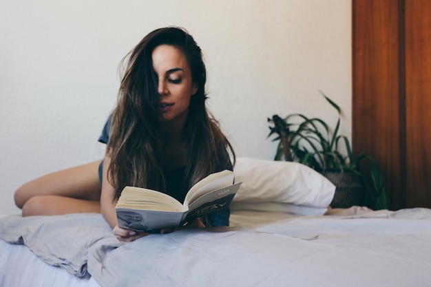 Photo gratuite livre de lecture de jolie femme au lit