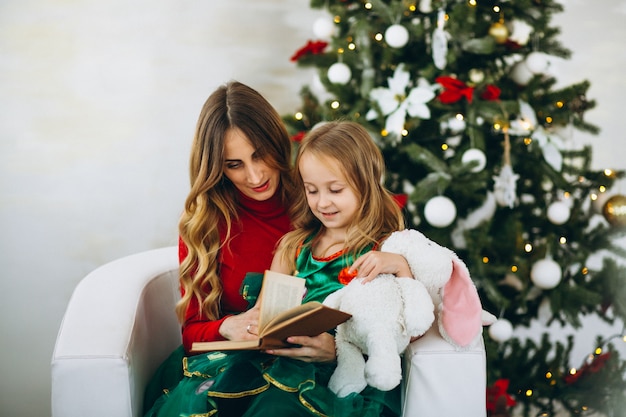 Livre de lecture de mère avec fille par sapin de Noël