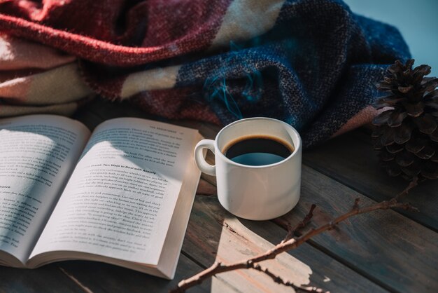 Livre près de la coupe et du plaid en laine sur la table