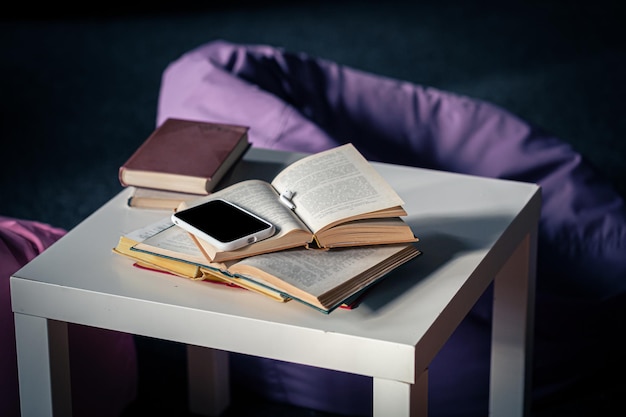 Photo gratuite livres sur une petite table blanche sur un fond flou de l'intérieur avec des poufs