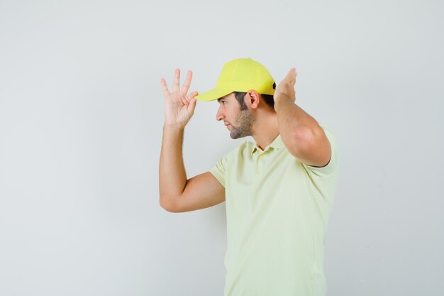 Livreur ajustant sa casquette en uniforme jaune et à la recherche de beau. vue de face.