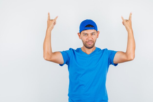 Livreur faisant symbole rock en t-shirt bleu, casquette et à la confiance