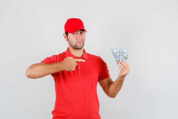 Livreur pointant sur les billets en dollars en t-shirt rouge