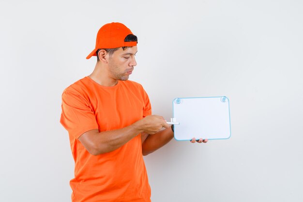 Livreur pointant le stylo au tableau blanc en t-shirt orange et vue de face de la casquette.