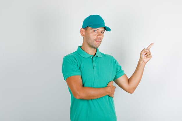 Livreur pointant vers le côté en t-shirt vert avec casquette et à la confiance.