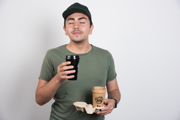 Photo gratuite livreur sentant l'arôme du café sur fond blanc.