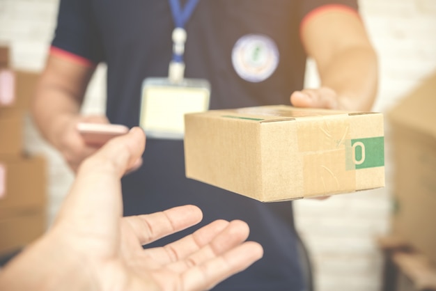 livreur souriant et tenant une boîte en carton