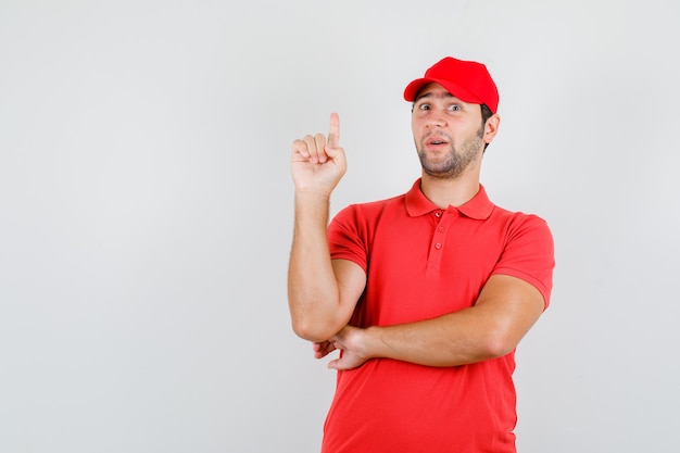 Livreur en t-shirt rouge, capuchon pointant le doigt vers le haut