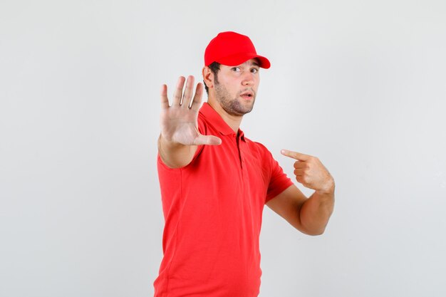 Livreur en t-shirt rouge, casquette pointant sur lui-même sans geste