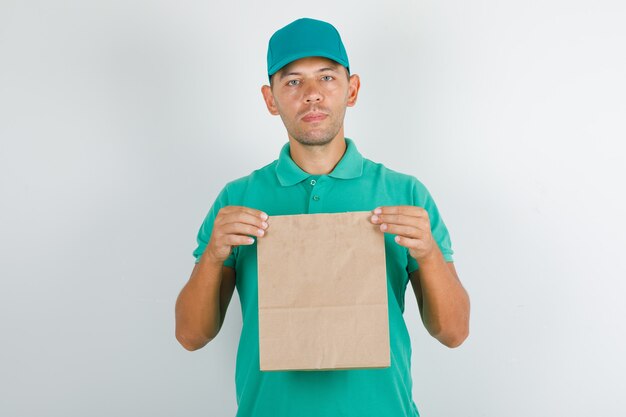 Livreur tenant un sac en papier brun en t-shirt vert avec casquette